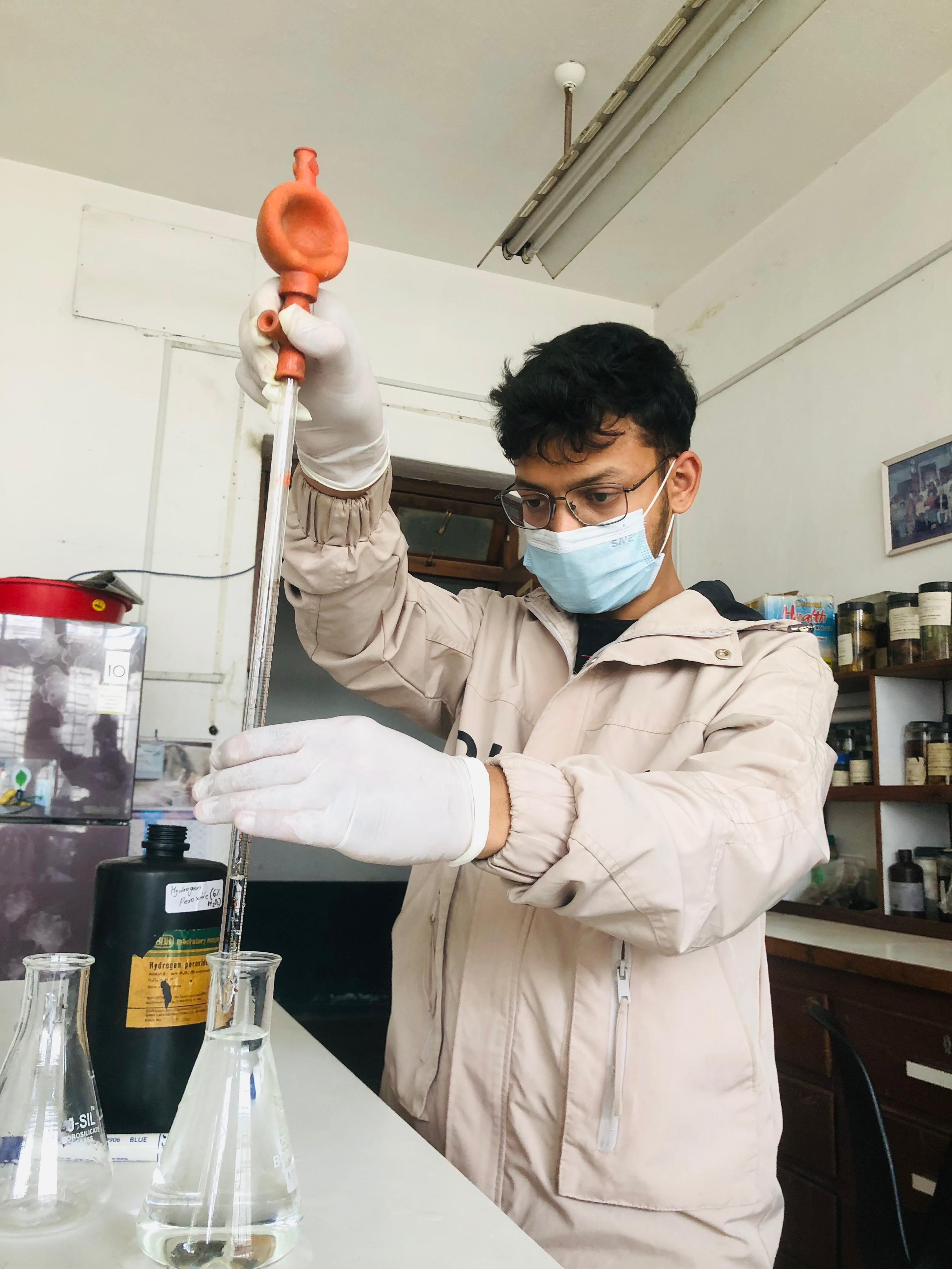  A person pouring a chemical solution into a beaker, representing the staining process for roots.